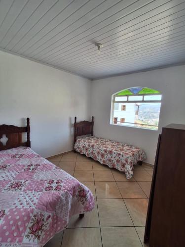 a bedroom with two beds and a window at Apartamento Confortável e Bem Localizado in Diamantina