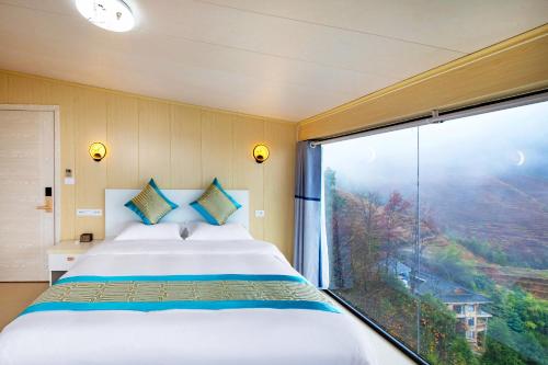 a bedroom with a bed and a large window at 龙脊梯田樹夏民宿 in Heping