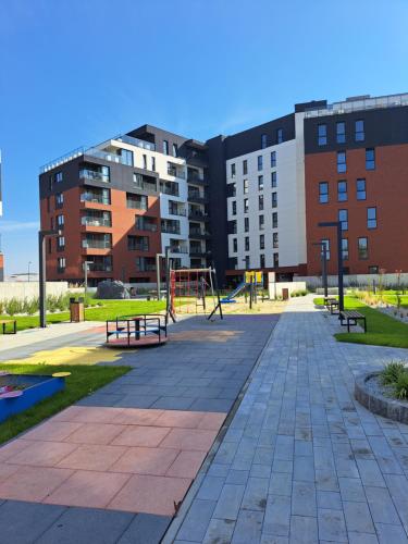 a park with benches and a playground in front of buildings at Apartament Cegiełka Mielec in Mielec