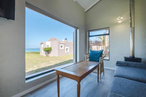 a living room with a table and a large window at Blue Bay Lodge in Saldanha