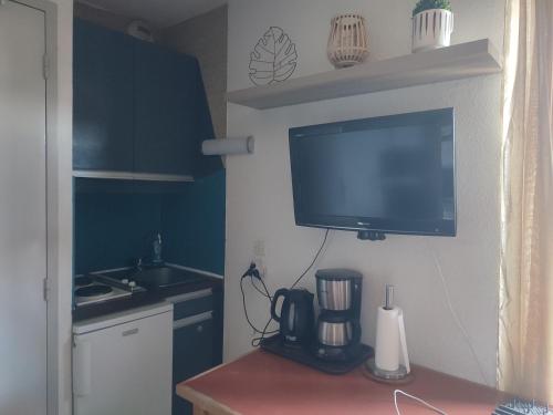 a television hanging on a wall in a kitchen at Le Cow'sy 1800 in Les Deux Alpes