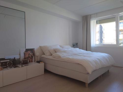 a white bedroom with a large bed and a mirror at Stilren leilighet midt på Lade in Trondheim