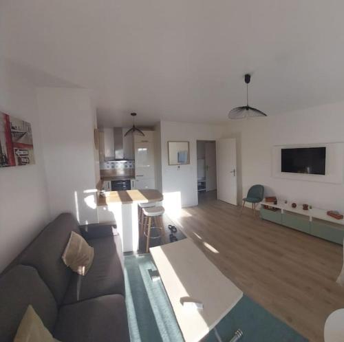 un salon avec un canapé et une cuisine dans l'établissement Bel appartement proche Paris, à Bois-Colombes