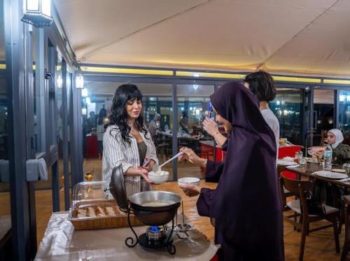 a group of women standing around a table in a restaurant at Stars Gate Camp in Al Wāşil
