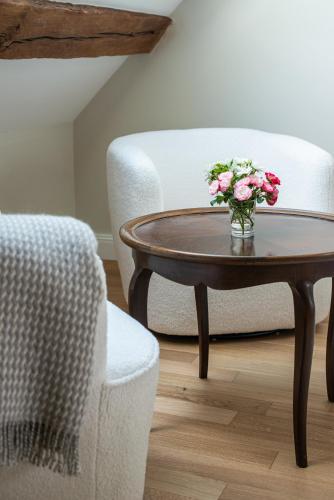 a vase of flowers on a table next to a chair at La Maison 1680 in Couches