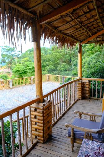 a wooden deck with a bench and a thatch roof at Pu Luong Jungle Lodge in Pu Luong
