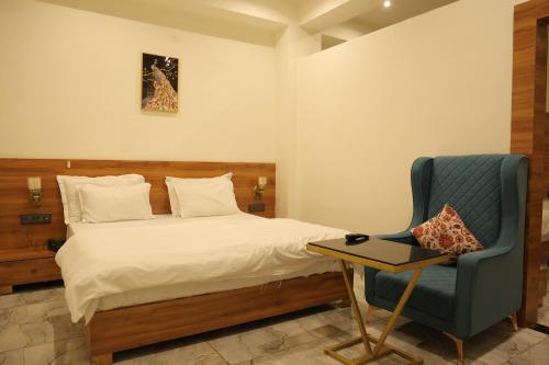 a bedroom with a bed and a blue chair at Hotel HS Inn Swiming Pool Room in Jaipur