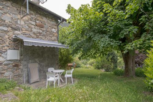 - une table et des chaises dans une cour à côté d'un bâtiment en pierre dans l'établissement Gîte Le Robinson, à Saint-Martin-Vésubie
