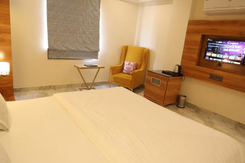 a bedroom with a bed and a chair and a television at Hotel HS Inn Swiming Pool Room in Jaipur