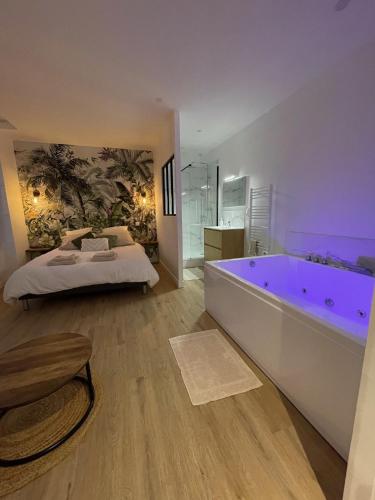 - une grande salle de bains avec une grande baignoire et un lit dans l'établissement Le Duplex : Balneo, lit queen size, à Beaugency