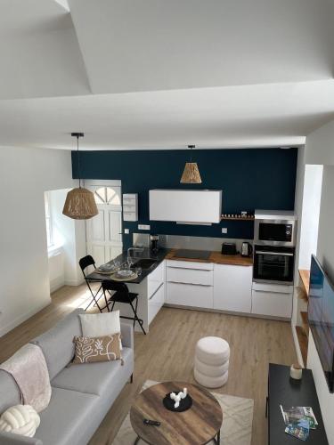 un salon avec un canapé et une cuisine dans l'établissement Le Duplex : Balneo, lit queen size, à Beaugency