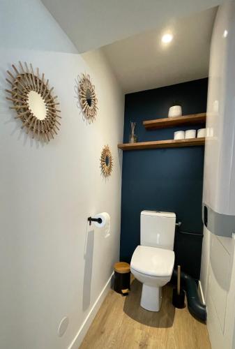 La salle de bains est pourvue de toilettes blanches et d'un mur bleu. dans l'établissement Le Duplex : Balneo, lit queen size, à Beaugency