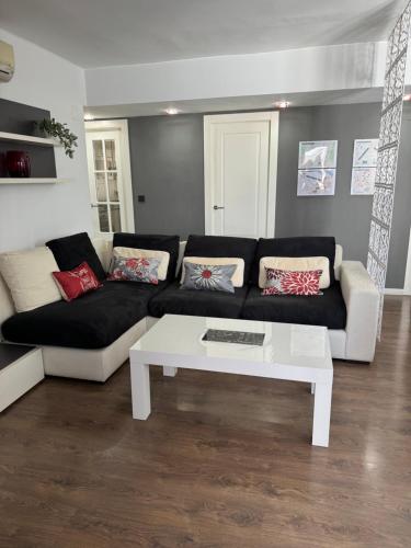 a living room with a black couch and a white coffee table at Atico Centro Sol y Vistas in Zaragoza
