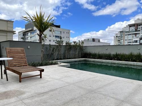una sedia in legno seduta accanto alla piscina di Belint Bela Cintra: A 5 Minutos da Paulista com Piscina no Rooftop a San Paolo
