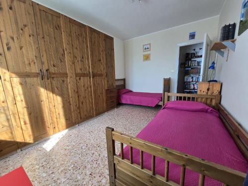 a bedroom with two beds and wooden cabinets at La casa dei libri in Caselle Torinese