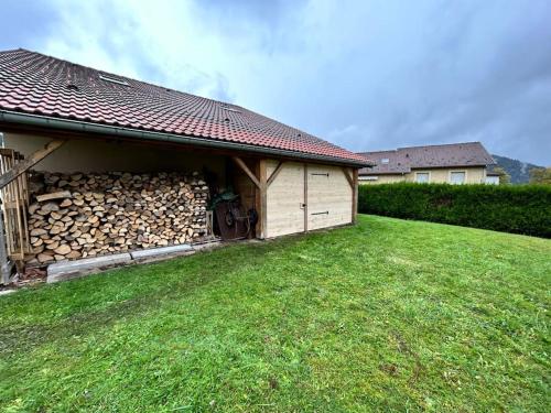 a building with a pile of fire wood next to a yard at La Magie entre deux lacs in Gérardmer