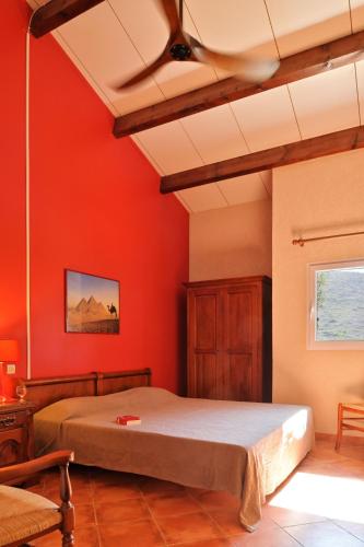 une chambre avec des murs rouges et un lit avec un plafond dans l'établissement U Casinu, à Piana