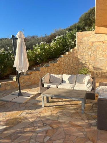 - un canapé installé sur une terrasse à côté d'un mur en pierre dans l'établissement Modern villa 5 double bedrooms, new AC, private pool and stunning view 800 m from beach, à Sagone