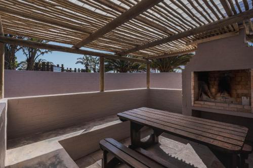 a wooden bench sitting on a patio with a fireplace at Blue Bay Lodge in Saldanha