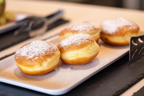 four donuts covered in powdered sugar on a tray at B&B Hotel Sonneck in Naz-Sciaves