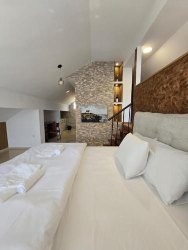 two white beds in a room with a fireplace at Hotel Mažijanik in Nikšić