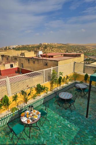 a balcony with tables and chairs on top of a building at Dar Golden Ziat in Fès