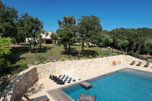 - une piscine avec un mur en pierre à côté d'une maison dans l'établissement Villa Arbevhio, à Bonifacio