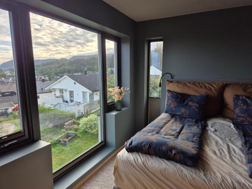 a bedroom with a bed and two large windows at New and trendy home with fjord view in Ranheim