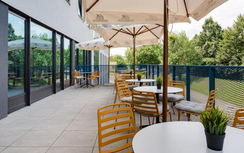 an outdoor patio with tables and chairs and umbrellas at Hotel Active Stadium in Lovosice