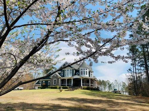 a large house on a hill with flowering trees at Chateau d' Amour - Where Love & Luxury Meet in Wake Forest