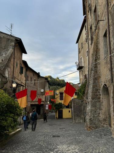 a group of people walking down a street with flags at la Contessa in Mazzano Romano