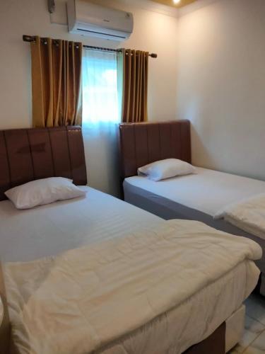 a bedroom with two beds and a window at Krui Ocean in Krui