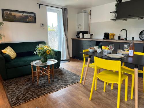 Il dispose d'une cuisine et d'un salon avec une table et des chaises jaunes. dans l'établissement Gite See You Soon - Maisonnette Green Lodge, à Ribeauvillé