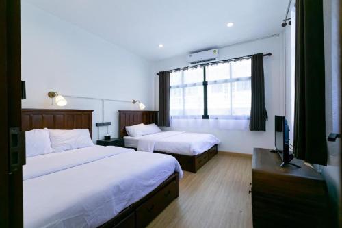 a hotel room with two beds and a television at Penthouse Lamoon in Bangkok