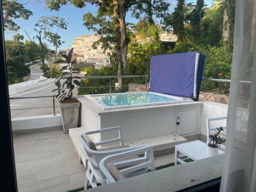 a hot tub sitting on a balcony with two chairs at Serenity Blue Las Terrenas in Las Terrenas