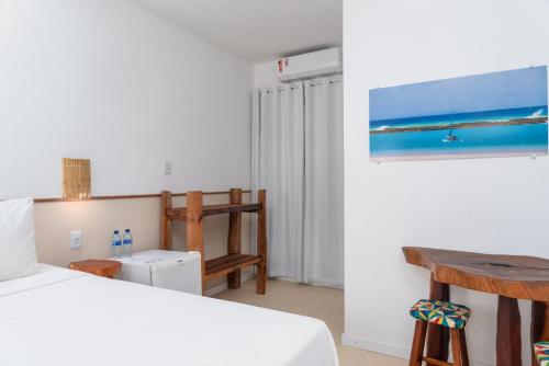 a bedroom with a bed and a table and a desk at Pousada Trilha do Mar in Praia do Frances