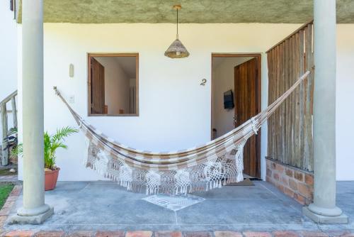 a hammock on the porch of a house at Pousada Trilha do Mar in Praia do Frances