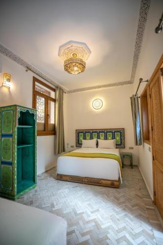 a bedroom with a large bed and a chandelier at Dar Golden Ziat in Fès