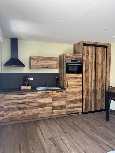 une cuisine avec des armoires en bois et un évier dans l'établissement LA VALENTINE Love room GITES DES 3 LAVOIRS, à Bourogne