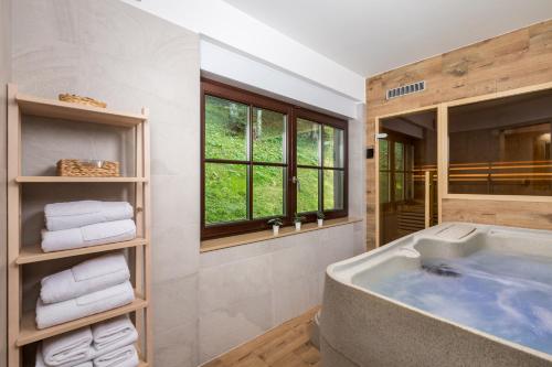 un bagno con ampia vasca e finestra di Gorska bajka - Jela, kuća za odmor i wellness a Stara Sušica