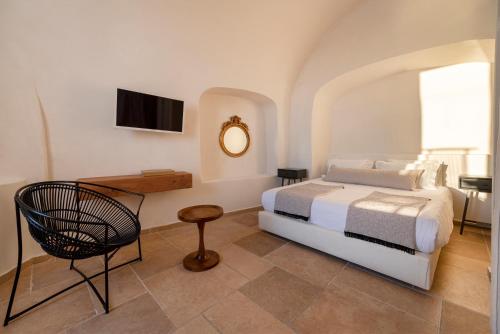 a bedroom with a bed and a table and a chair at La Maltese Estate in Imerovigli