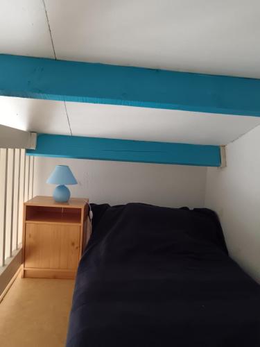 un lit avec une tête de lit bleue et une lampe bleue dans l'établissement Appartement vue port - Port Leucate, à Port-Leucate