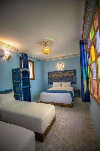 two beds in a room with blue walls and windows at Dar Golden Ziat in Fès