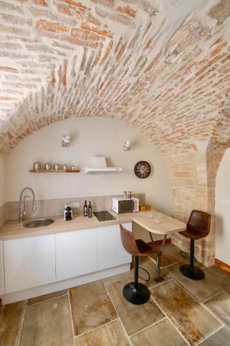 une cuisine avec une table et un plafond en pierre dans l'établissement Les petites Voutes, à Saint-Gilles