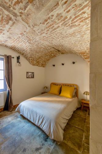 - une chambre avec un lit et un plafond en pierre dans l'établissement Les petites Voutes, à Saint-Gilles