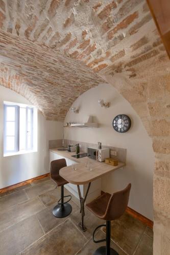 une cuisine avec une table, deux chaises et une horloge dans l'établissement Les petites Voutes, à Saint-Gilles