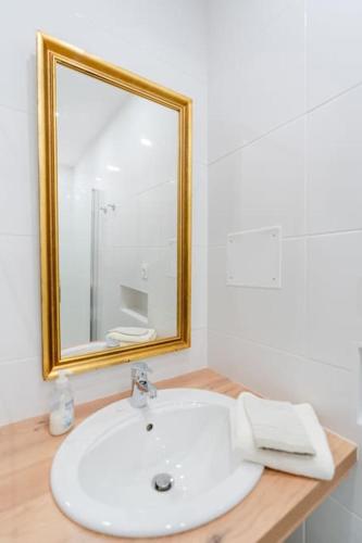 une salle de bain avec un lavabo blanc et un miroir dans l'établissement La Livrée des papes, à Châteauneuf-du-Pape