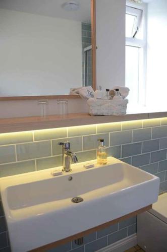 a white sink in a bathroom with a mirror at Macks Shack at Machrimore in Wells next the Sea