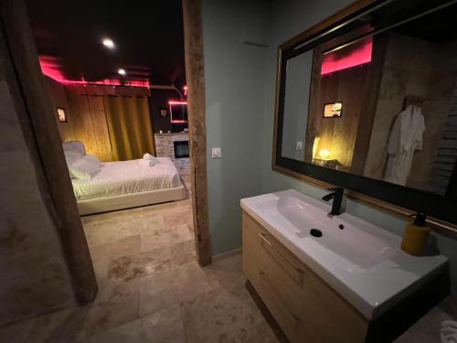 a bathroom with a sink and a mirror and a bed at Le Lodge des Charmes 5 étoiles in Lèves
