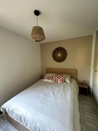 - une chambre avec un lit blanc et un ventilateur dans l'établissement Le Baronnie F2 calme proche mer, au Grau-du-Roi